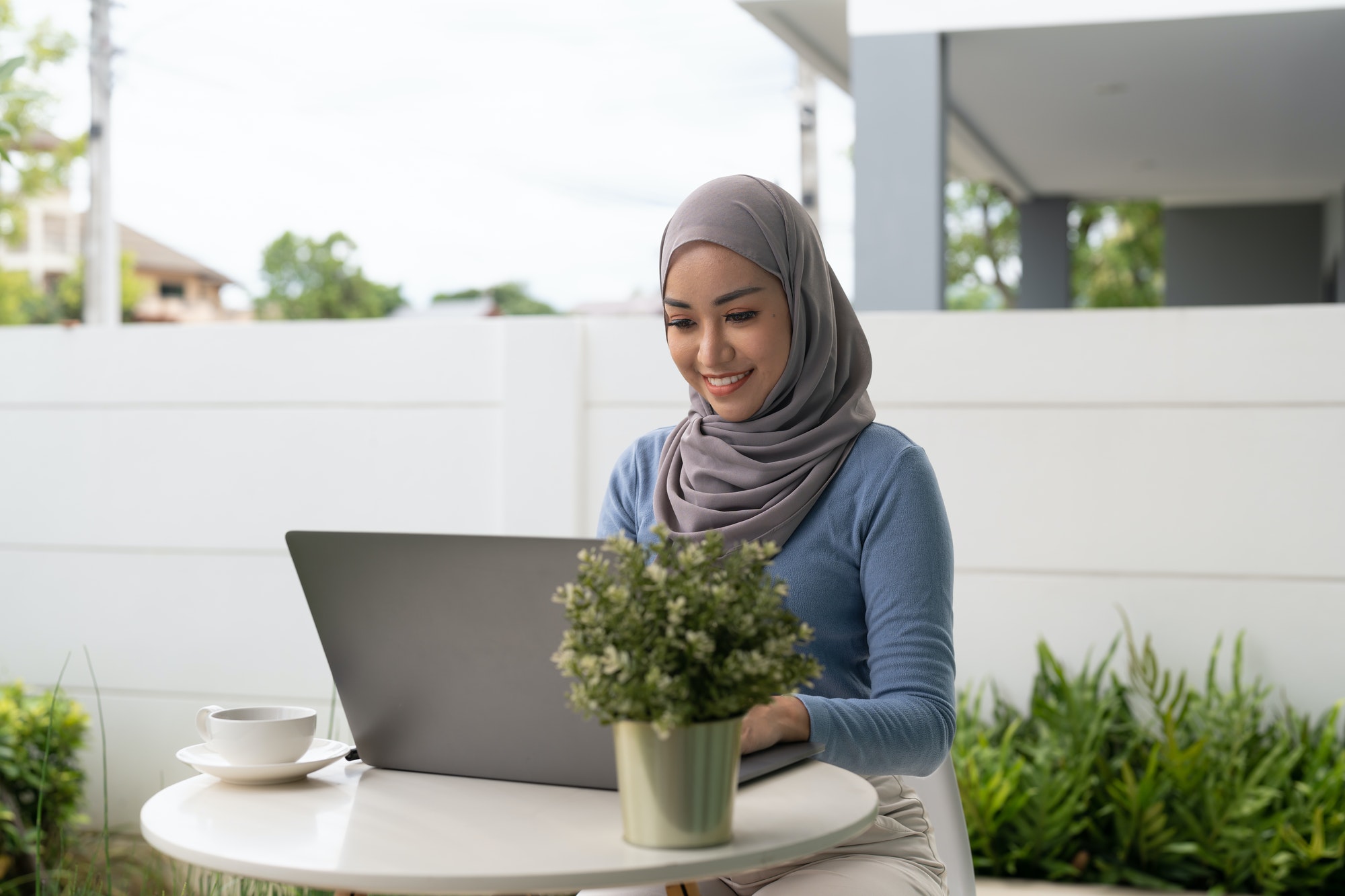 Portrait of Muslim asian woman in hijab using laptop at home.