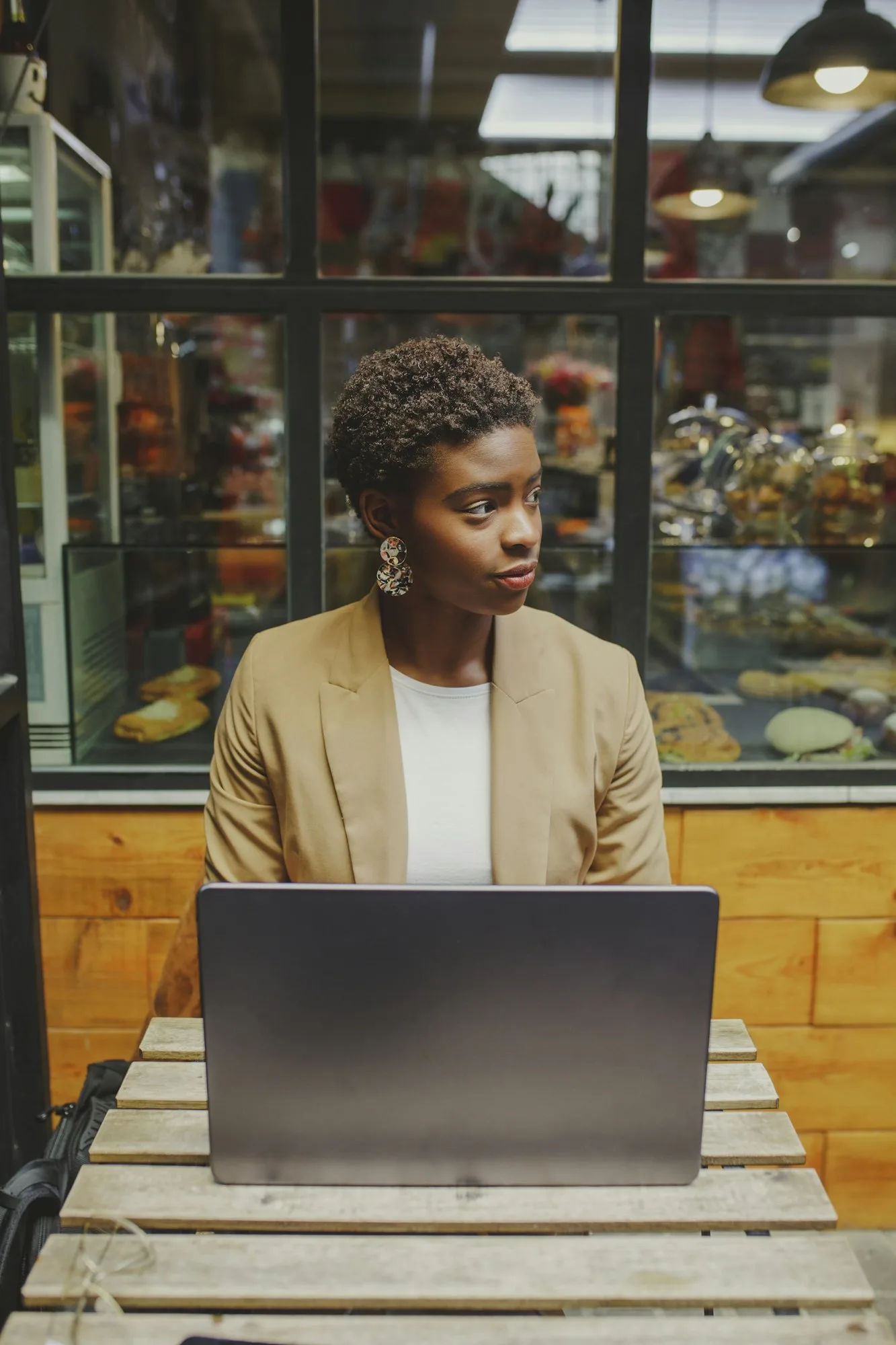 Smiling Black woman sitting at table with laptop in cafe